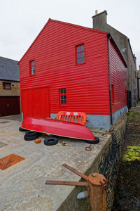 Red house on street by building against sky