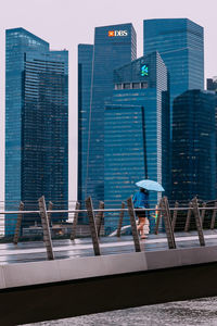 Modern building by swimming pool in city against sky