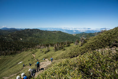 High angle view of people on mountain against clear blue sky