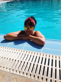 Portrait of woman wearing sunglasses resting at poolside