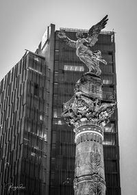 Low angle view of statue against modern building