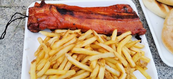 High angle view of meat and fries in plate on table