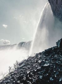 Low angle view of waterfall against rainbow in sky