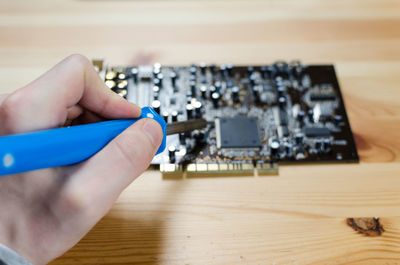 Cropped image of man soldering circuit board at table