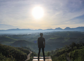 Rear view of man looking at mountains against sky