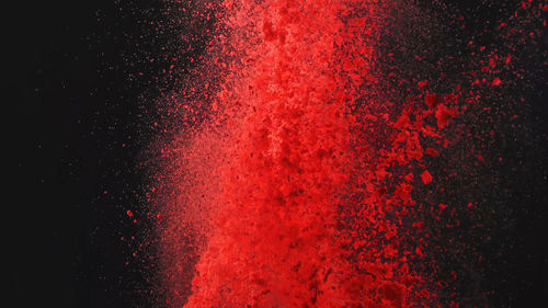 Close-up of powder paints exploding against black background