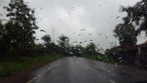 Surface level of wet road against cloudy sky