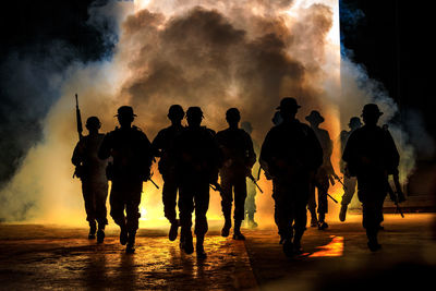 Silhouette army soldiers walking against smoke at night