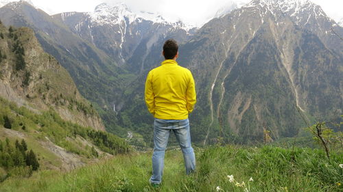 Rear view of man standing on mountain against sky