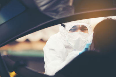 Asian woman drive thru covid-19 testing with ppe medical staff, covid testing temp while checking