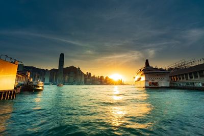 Scenic view of sea by buildings against sky during sunset