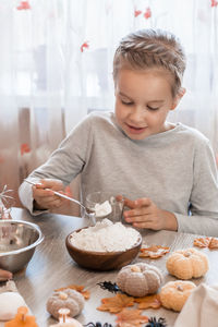 Cute little girl puts flour in a glass for cooking ginger dough for making cookies for halloween 