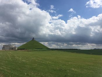 Scenic view of grassy field against cloudy sky