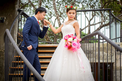 Couple kissing on railing against clear sky