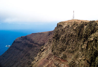 Cliff by sea against sky