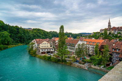 Buildings by river against sky