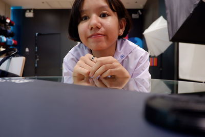 Portrait of girl sitting at table in laboratory