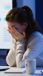 Side view of young woman using laptop at home