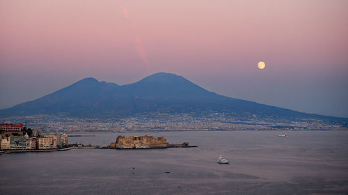 Scenic view of sea and mountains against sky at sunset