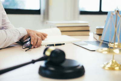 Cropped image of lawyer with gavel and weight scale in foreground