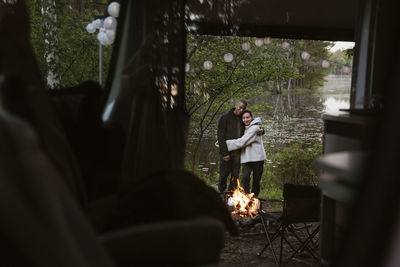 Couple hugging by campfire