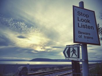 Sign board against cloudy sky