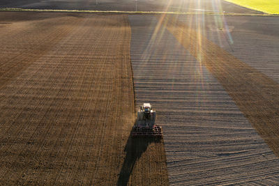 Aerial view of tractor plowing field at sunset