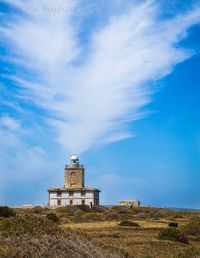 Lighthouse on field against sky