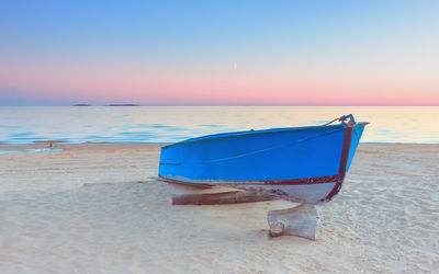 Deck chairs on beach against sky during sunset