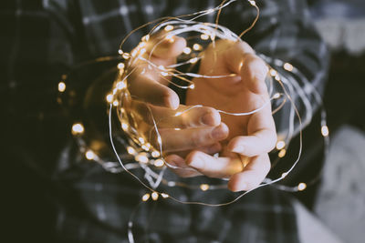 Midsection of man holding string light