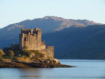 Eilean donan castle by river against mountains