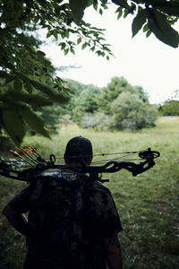 Rear view of man holding umbrella on field