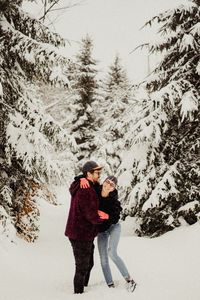 Cheerful couple standing on snow covered land during winter
