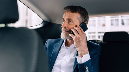 Businessman talking over mobile phone in car