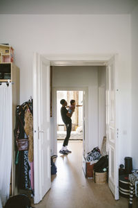 Young man carrying daughter seen through doorway at home