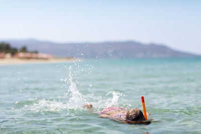 Man swimming in sea against sky