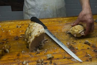 High angle view of hand holding burger along with knife