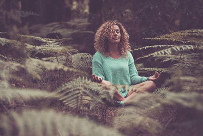 Woman meditating amidst forest