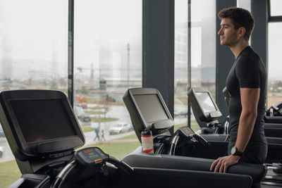 Side view of young man looking through window