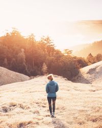 Rear view of young woman walking on landscape