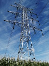 Low angle view of electricity pylon on field against sky