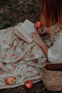 Redhead woman holding an apple and reading book