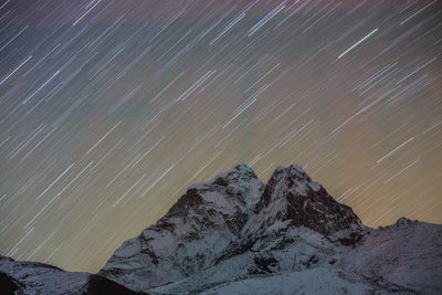 Star trails captured in a long exposure image of ama dablam in nepal.