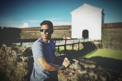 Side view of man standing by retaining wall against bridge