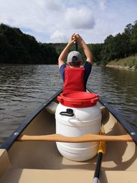 Rear view of man in boat against lake