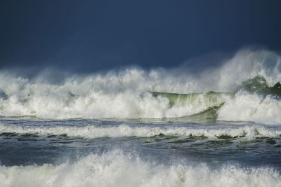 Waves splashing in sea against sky