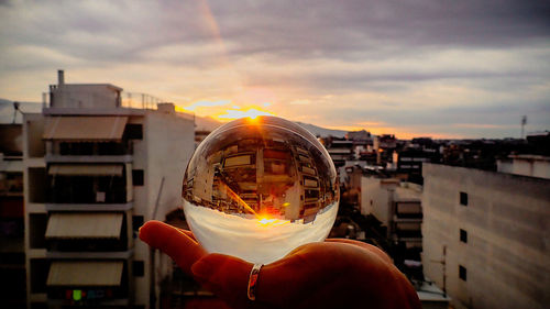 Person holding cityscape against sky in city