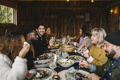 Portrait of smiling man enjoying with male and female friends during social gathering