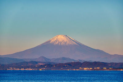 Scenic view of sea and snowcapped mountain against sky during sunrise