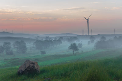 Scenic view of wind turbine field against sky during sunset